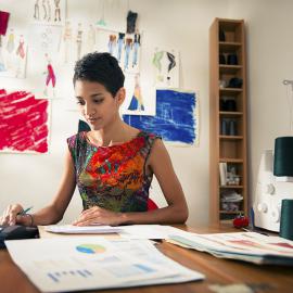 a women sitting and behind her a lot a paintings on the wall